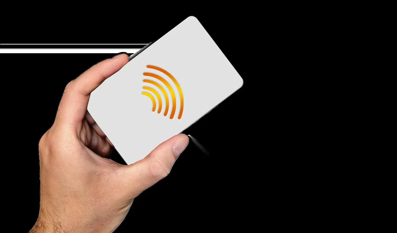 Eine Hand hält eine hellgraue Plastikkarte mit orangefarbenem Symbol für kontaktloses Bezahlen vor schwarzem Hintergrund